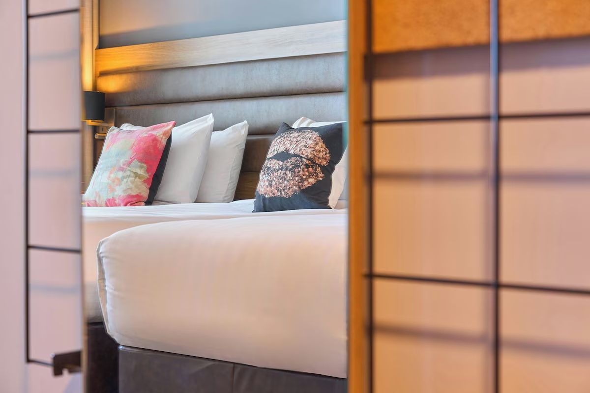 Close-up of twin beds at Moxy Dublin City, stylish hen party accommodation in Dublin with colourful cushions and warm modern finishes.