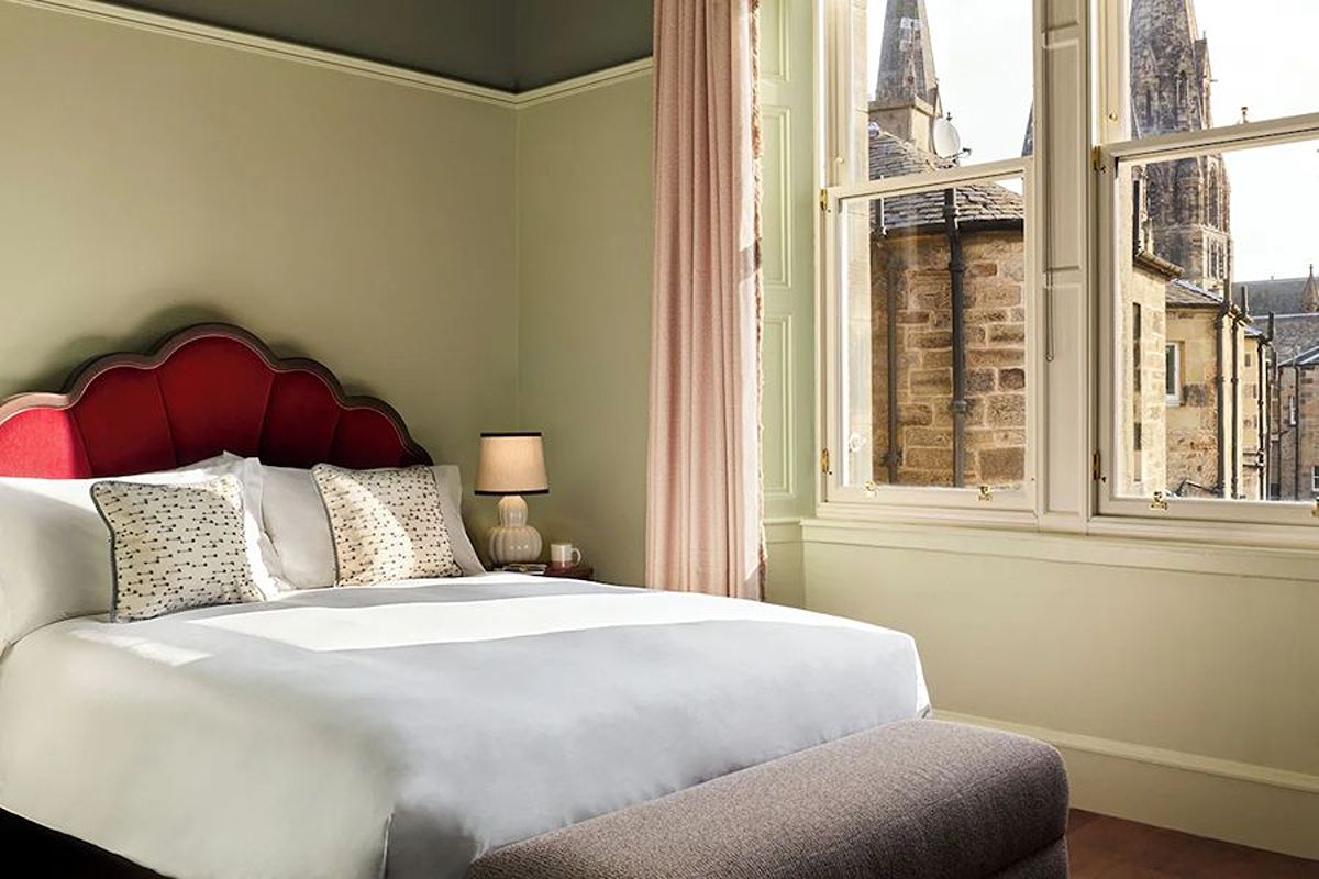 Bright bedroom at The Hoxton Edinburgh, an Edinburgh hen weekend hotel with soft green interiors and views across the surrounding city architecture.