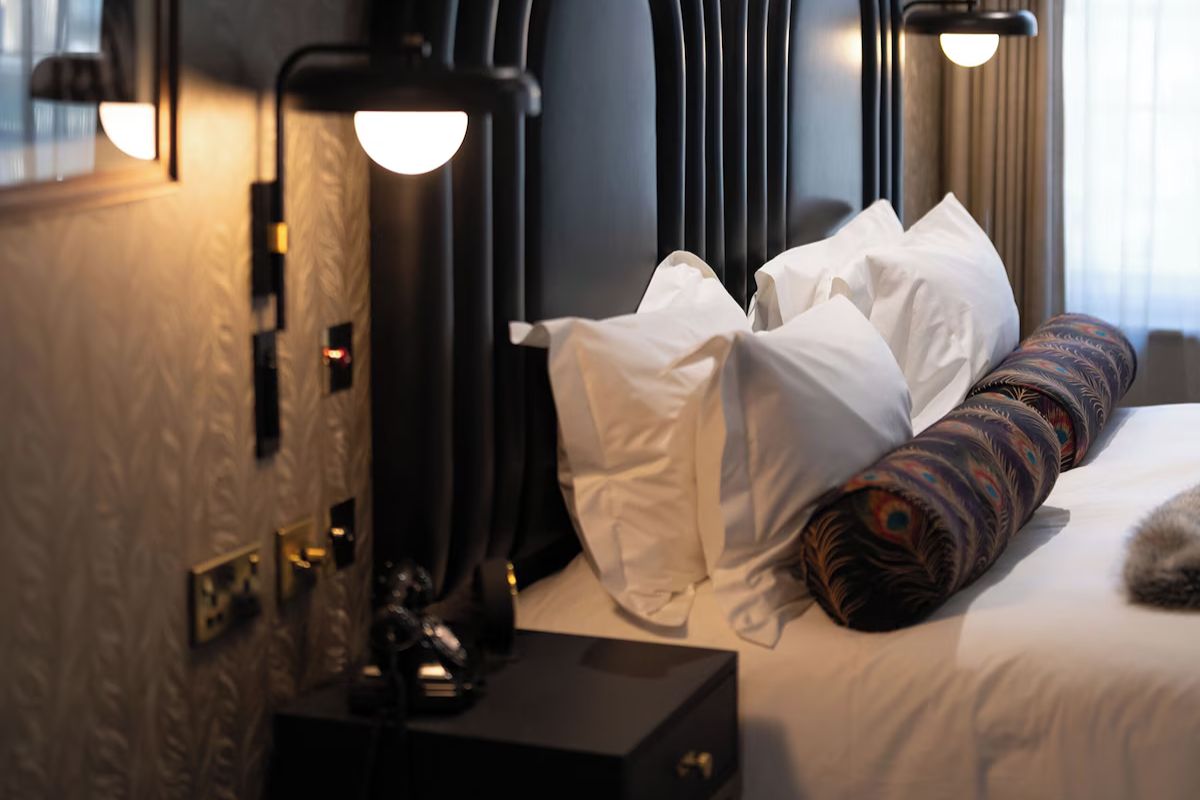 Bedroom at The Rex Newcastle with monochrome styling and peacock-print cushions.