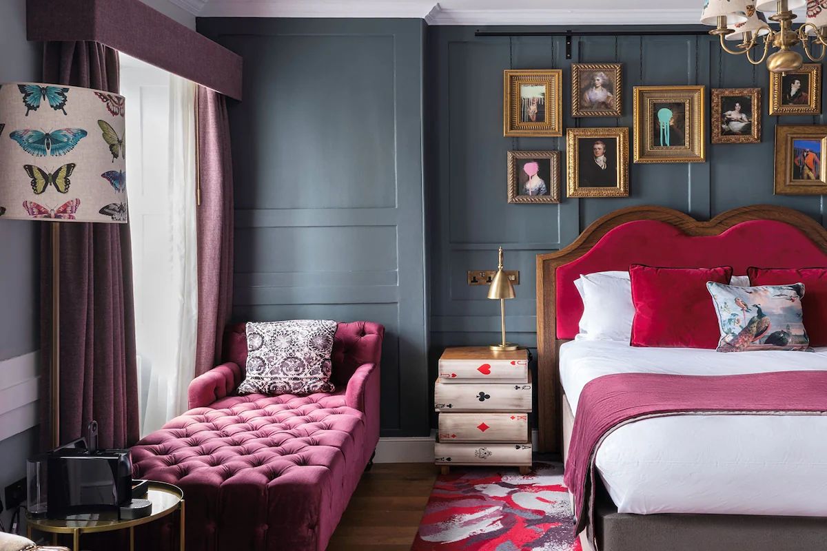 Colourful bedroom at Hotel Indigo Bath, a boutique Bath hen weekend hotel with bold pink furnishings, dark walls and playful artwork.