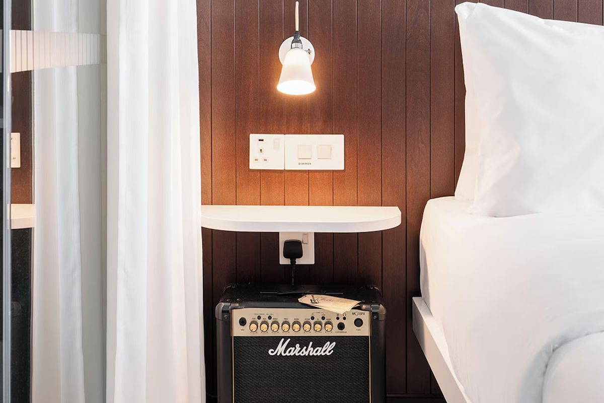 Bedroom detail at Ruby Molly Hotel Dublin showing dark wood panelling, bedside lighting and a Marshall speaker.