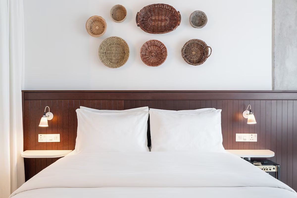 Bedroom at Ruby Molly Hotel Dublin with a white bed, dark wood panelling and woven wall decor.