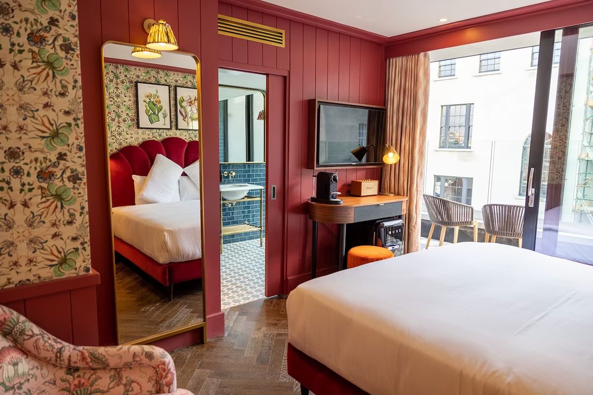 Colourful bedroom at The Dean Dublin, a central Dublin hen weekend hotel with bold red walls, floral details and a private balcony.