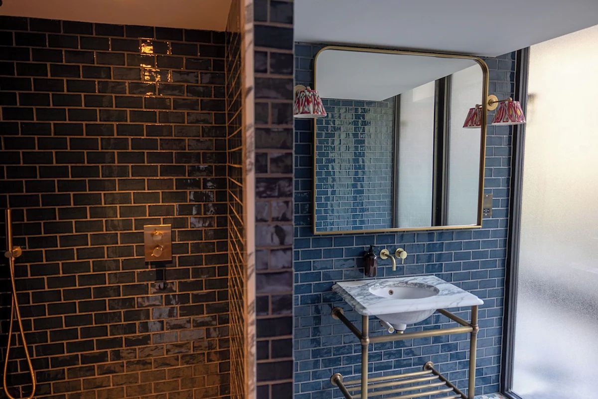 Bathroom at The Dean Dublin, a boutique Dublin hen weekend hotel with glossy blue tiles, brass fittings and a marble-topped basin.