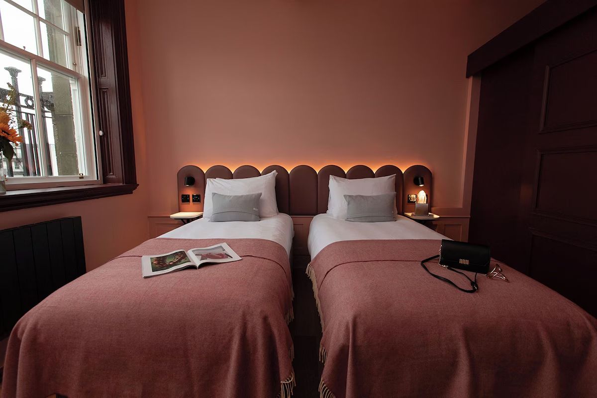 Twin bedroom at The Address Wren Glasgow with soft pink tones, modern lighting and proper single beds for friends sharing.