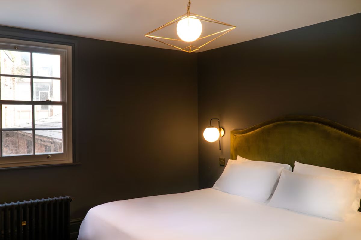 Stylish bedroom at 19 Duke Street Liverpool with dark walls and a velvet headboard.