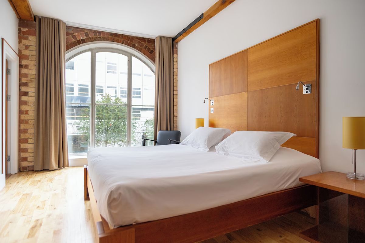Bright bedroom at Hope Street Hotel with exposed brick and large windows.