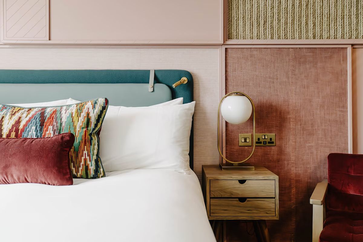 Bedroom detail at The Halyard Liverpool with colourful cushions and warm textures.