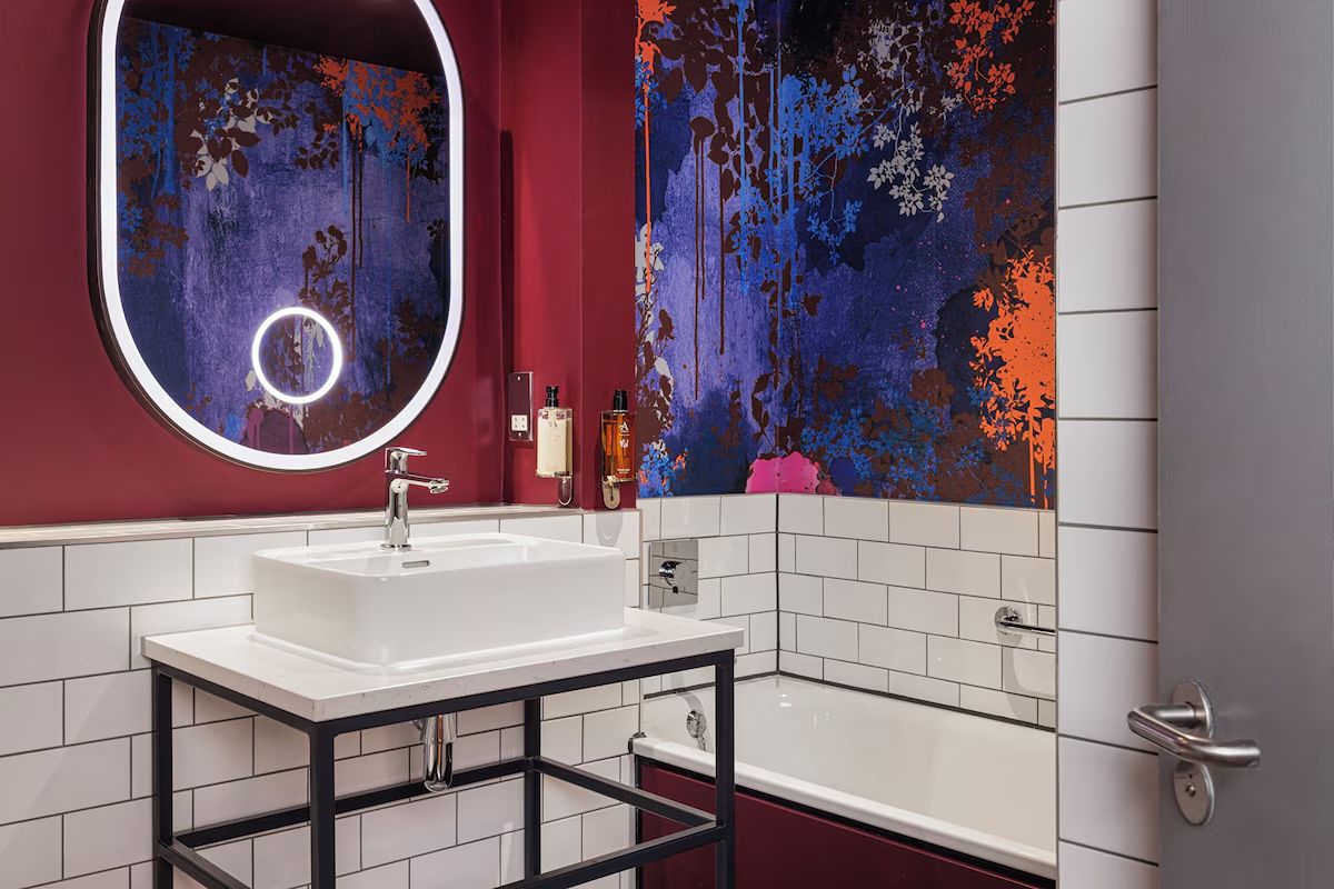 Bathroom at Malmaison Newcastle with bold artwork, tiled walls and contemporary fittings.