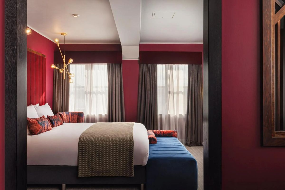 Moody bedroom at Malmaison Newcastle with deep red walls and a spacious bed for a Newcastle weekend stay.